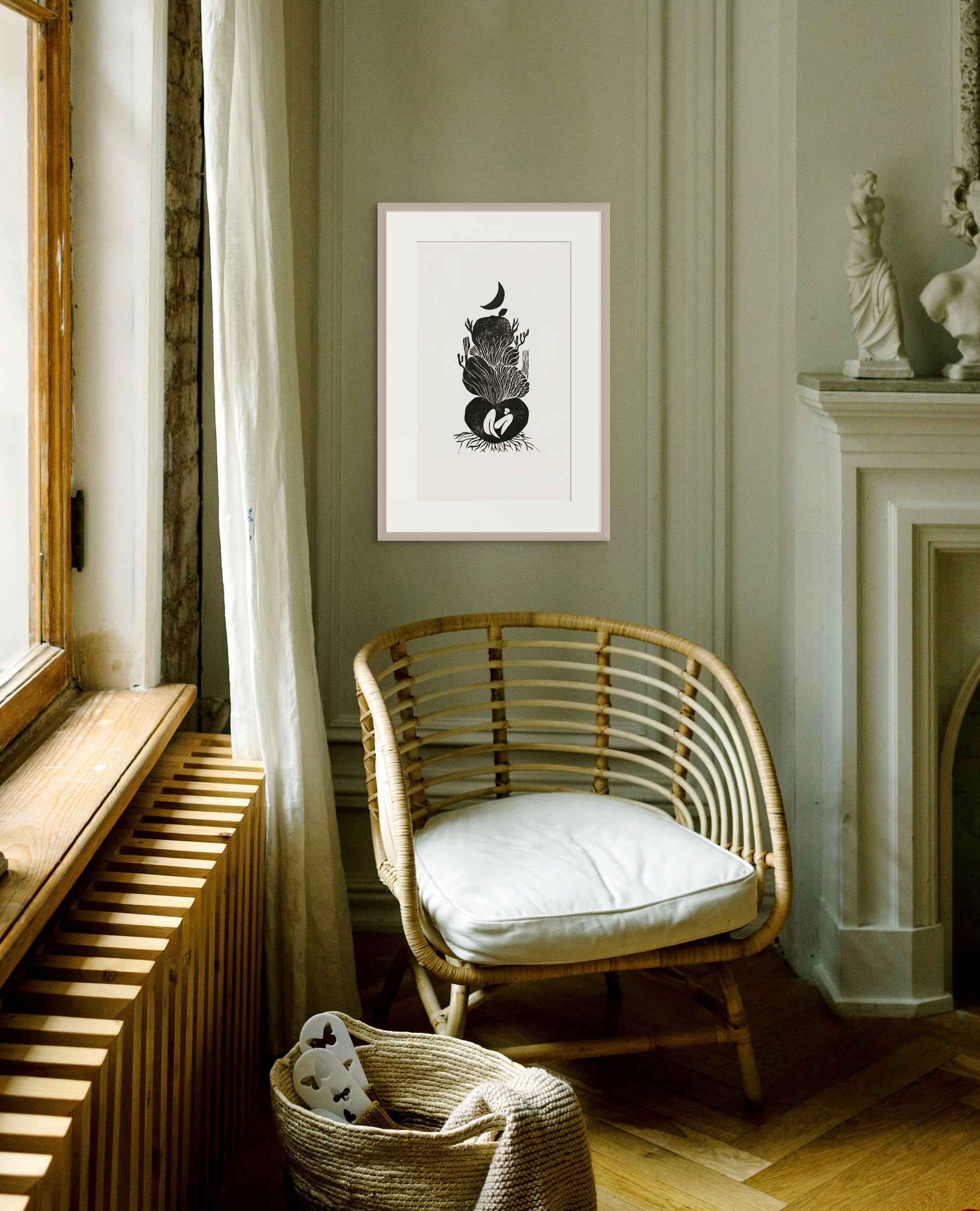 Rattan chair with white cushion in a room with framed artwork on the wall.